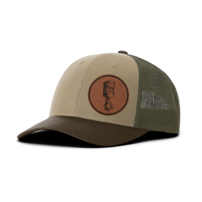 Trucker hat with angry piston patch, sand front and dark olive mesh back panels.