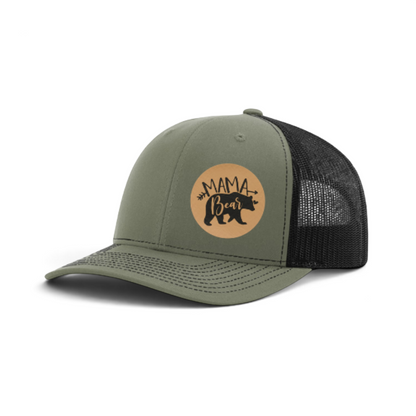 Olive green trucker hat with round tan Mama Bear patch and black mesh back.