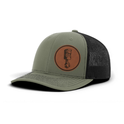 Green trucker cap with circular piston patch and black textured mesh panels