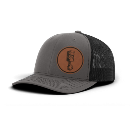 Gray trucker cap with circular piston patch and black textured mesh panel