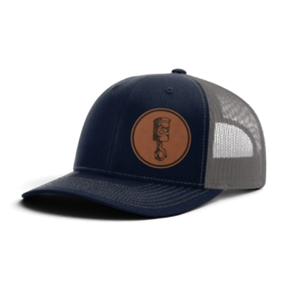 Navy trucker cap with circular piston patch and gray-and-white textured mesh