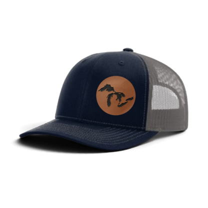 Navy trucker hat with tan patch and black silhouette; light gray mesh back panel