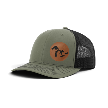 Olive green trucker hat with burnt orange tan patch and black silhouette; dark gray mesh