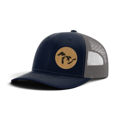 Navy trucker hat with tan patch and black silhouette; light gray mesh side panels