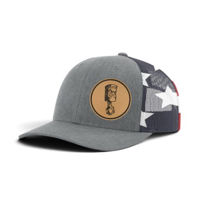 Gray trucker cap with circular piston patch and black/white star-pattern mesh