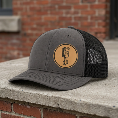 Gray trucker hat with round angry piston patch and black mesh side panels