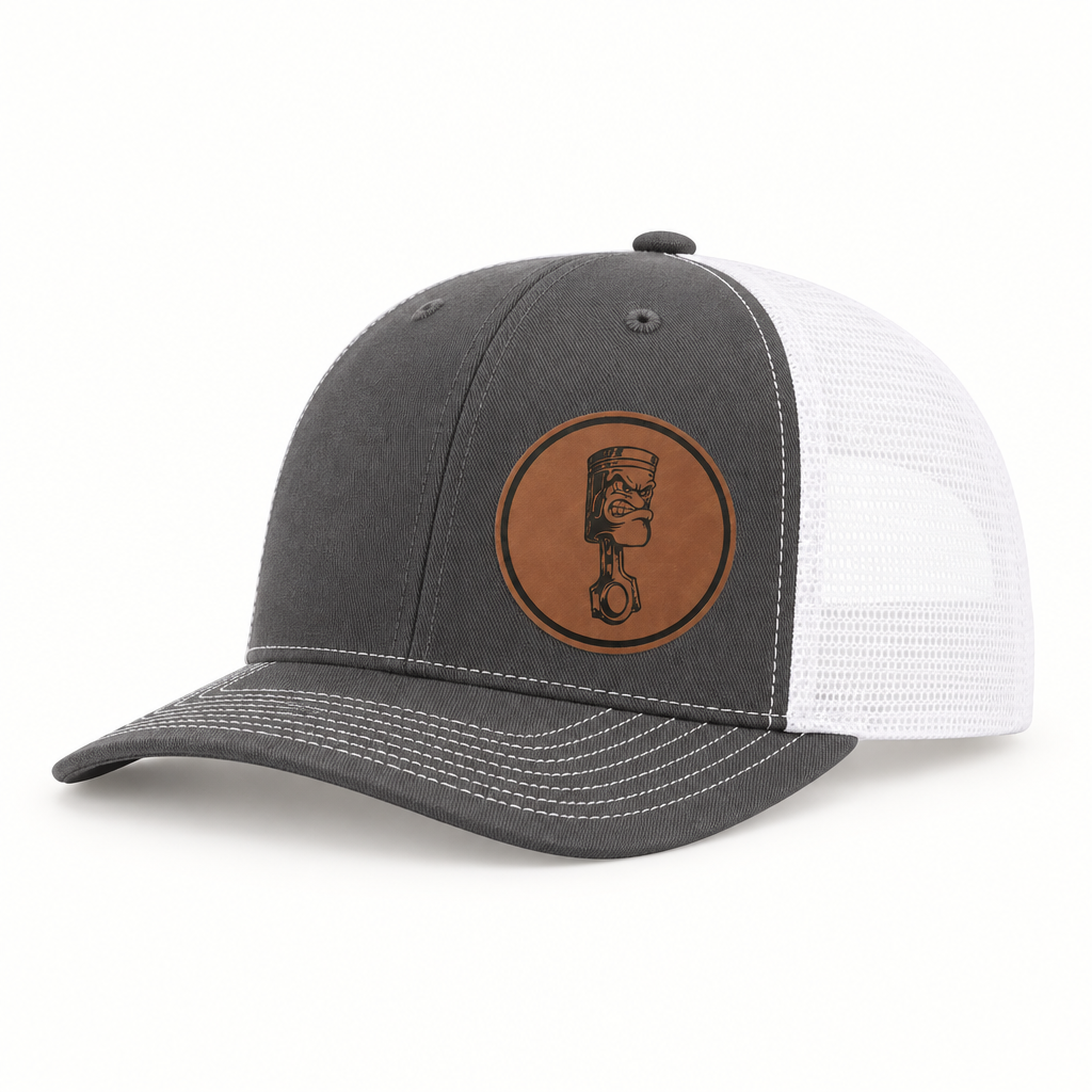 Dark gray trucker hat with white mesh back and round angry piston patch on front.