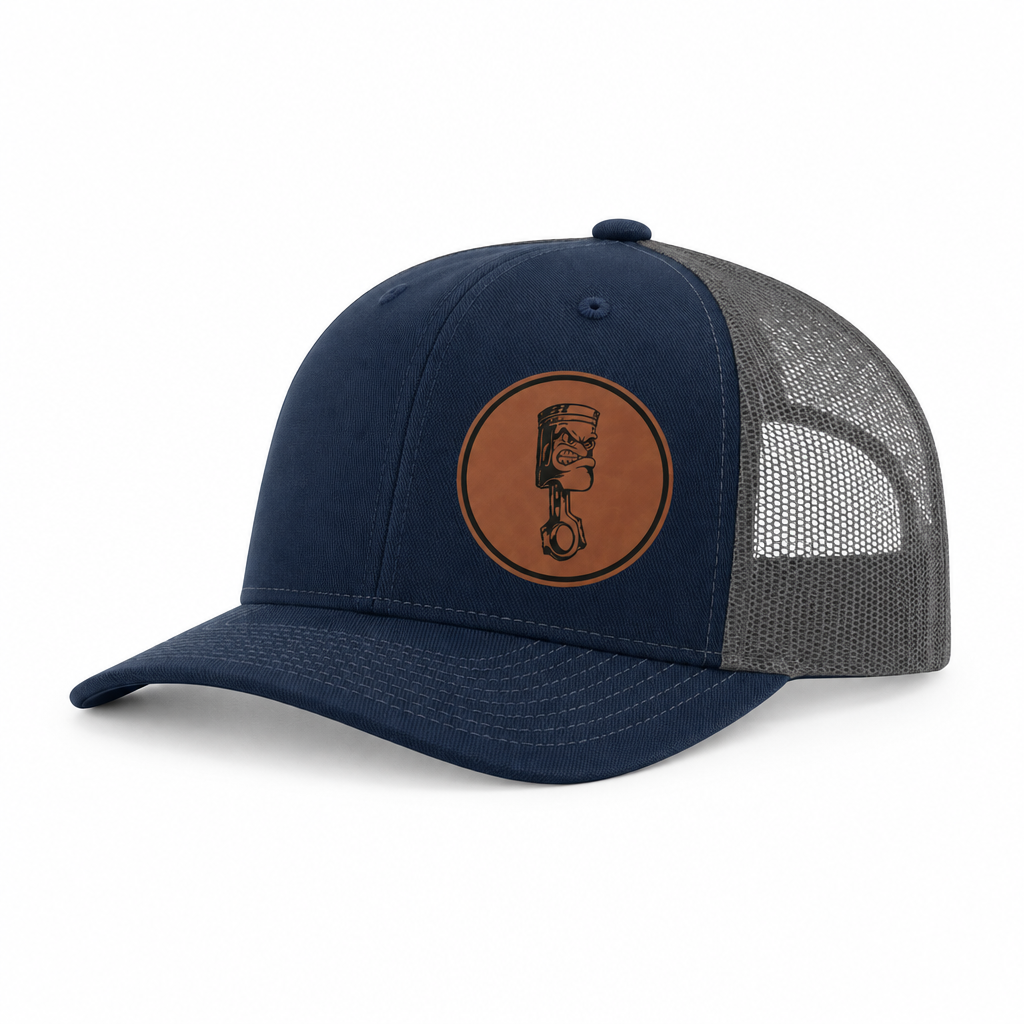 Blue trucker hat with gray mesh back and round angry piston patch on front.
