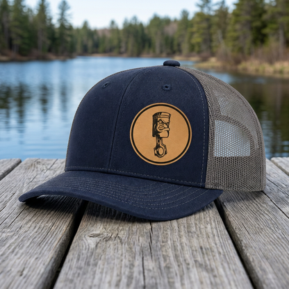 Navy trucker hat with round angry piston patch and dark gray mesh side panels