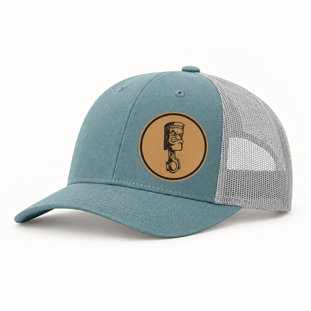 Teal canvas trucker hat with gray mesh back and round Angry Piston patch