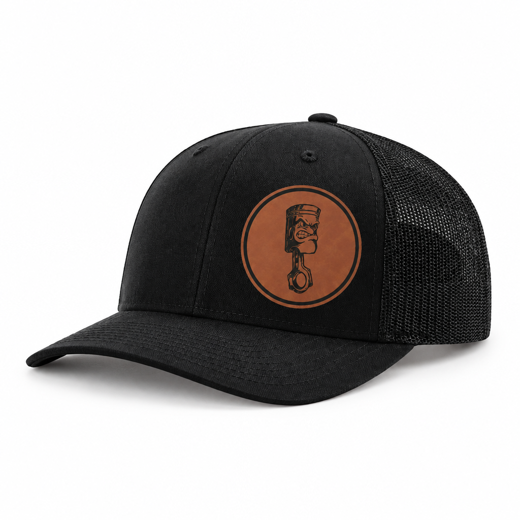 Black canvas trucker hat with black mesh back and Angry Piston logo patch