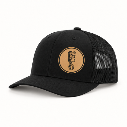 Black canvas trucker hat with black mesh back and round Angry Piston patch