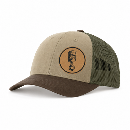 Beige canvas trucker hat with dark brown mesh back and round Angry Piston patch