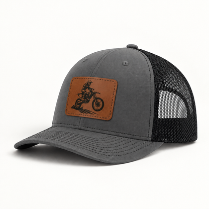 Dark gray trucker hat with brown dirt bike patch and black mesh side panels