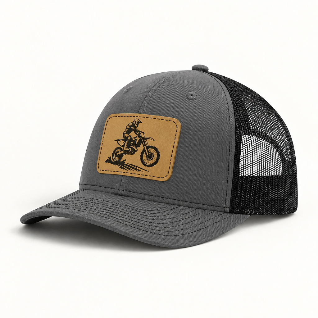 Dark gray trucker hat with tan dirt bike patch and black mesh side panels