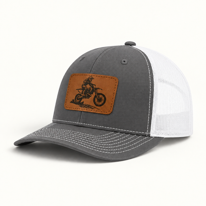 Dark gray trucker hat with brown dirt bike patch and white mesh side panels