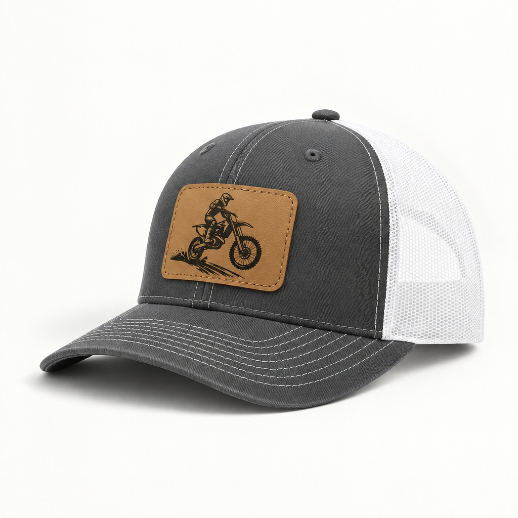 Dark gray trucker hat with tan dirt bike patch and white mesh side panels