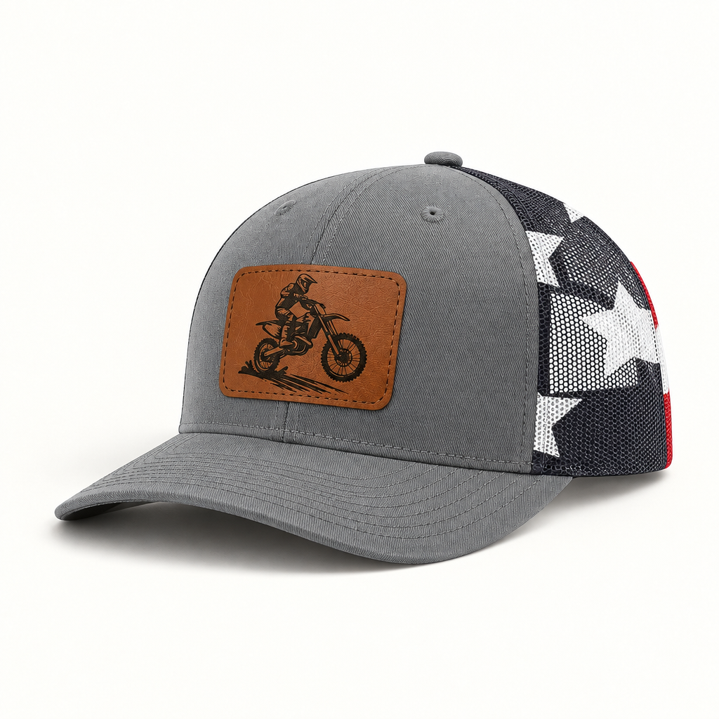 Dark gray trucker hat with tan dirt bike patch and black mesh side panels with star pattern