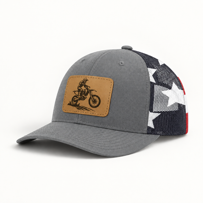 Dark gray trucker hat with tan dirt bike patch and black mesh side panels with star pattern