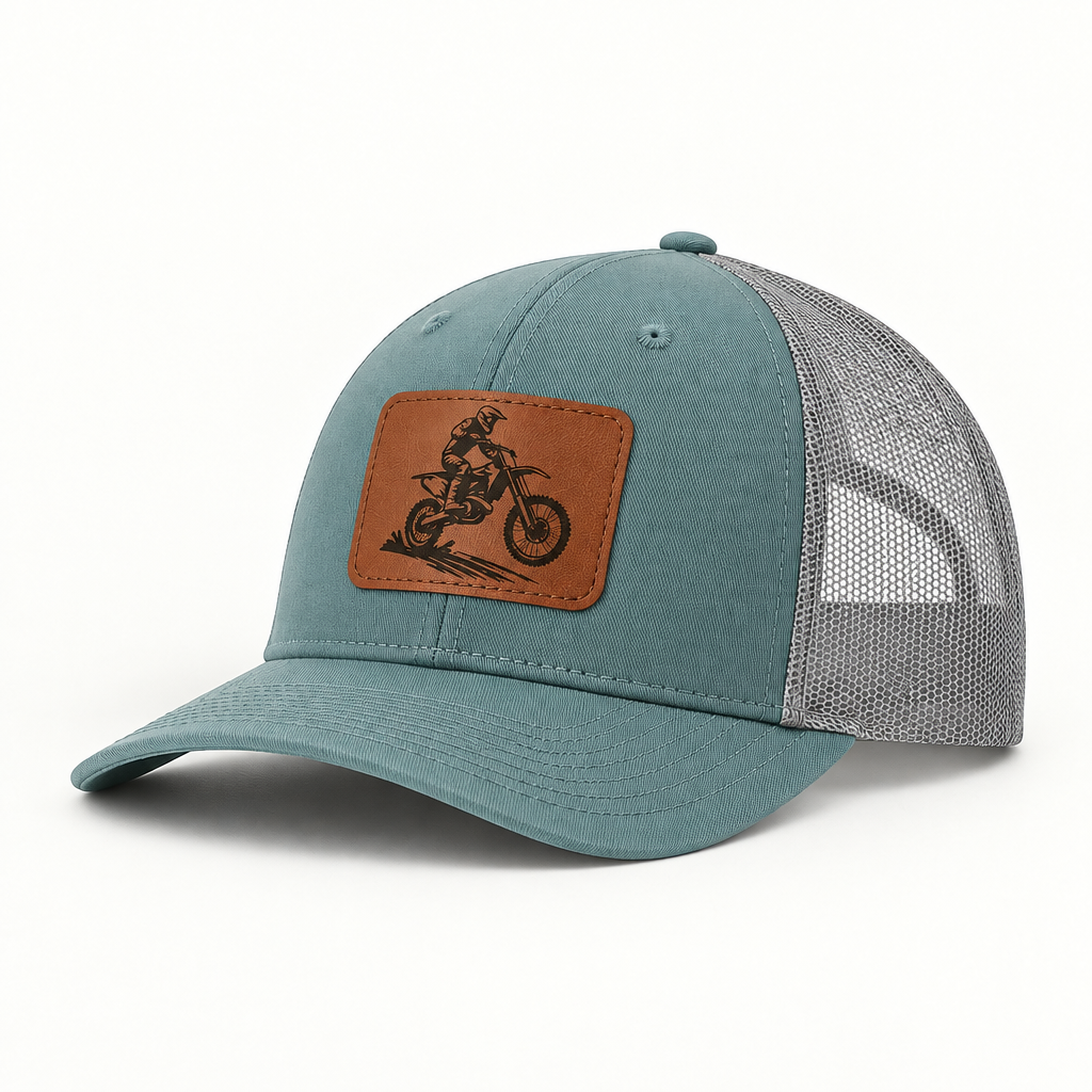 Trucker hat in teal with gray mesh; dirt bike rider patch in tan leather on front.