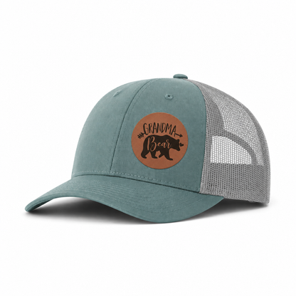 Teal trucker hat angled view with tan mesh sides and Grandma Bear patch.