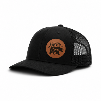 Black trucker hat angled view with brown Grandma Bear patch and mesh side panel.
