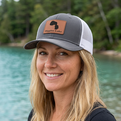 Charcoal and white mesh trucker hat with Higgins Lake tan patch on front