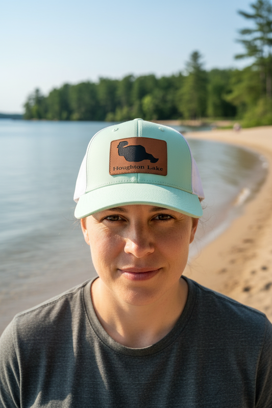 Houghton Lake Michigan leatherette patch trucker hat worn by model on largest inland lake shoreline with pine trees – Keeko Designs