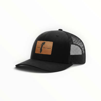 Black trucker cap with black mesh and brown Lake Michigan front patch, angled
