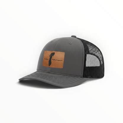 Charcoal trucker hat with tan patch and black mesh back, low-profile crown