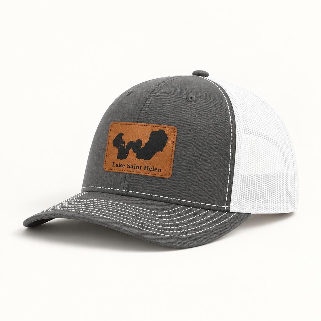 Dark gray trucker hat with tan logo patch, white mesh back, curved brim, snap button