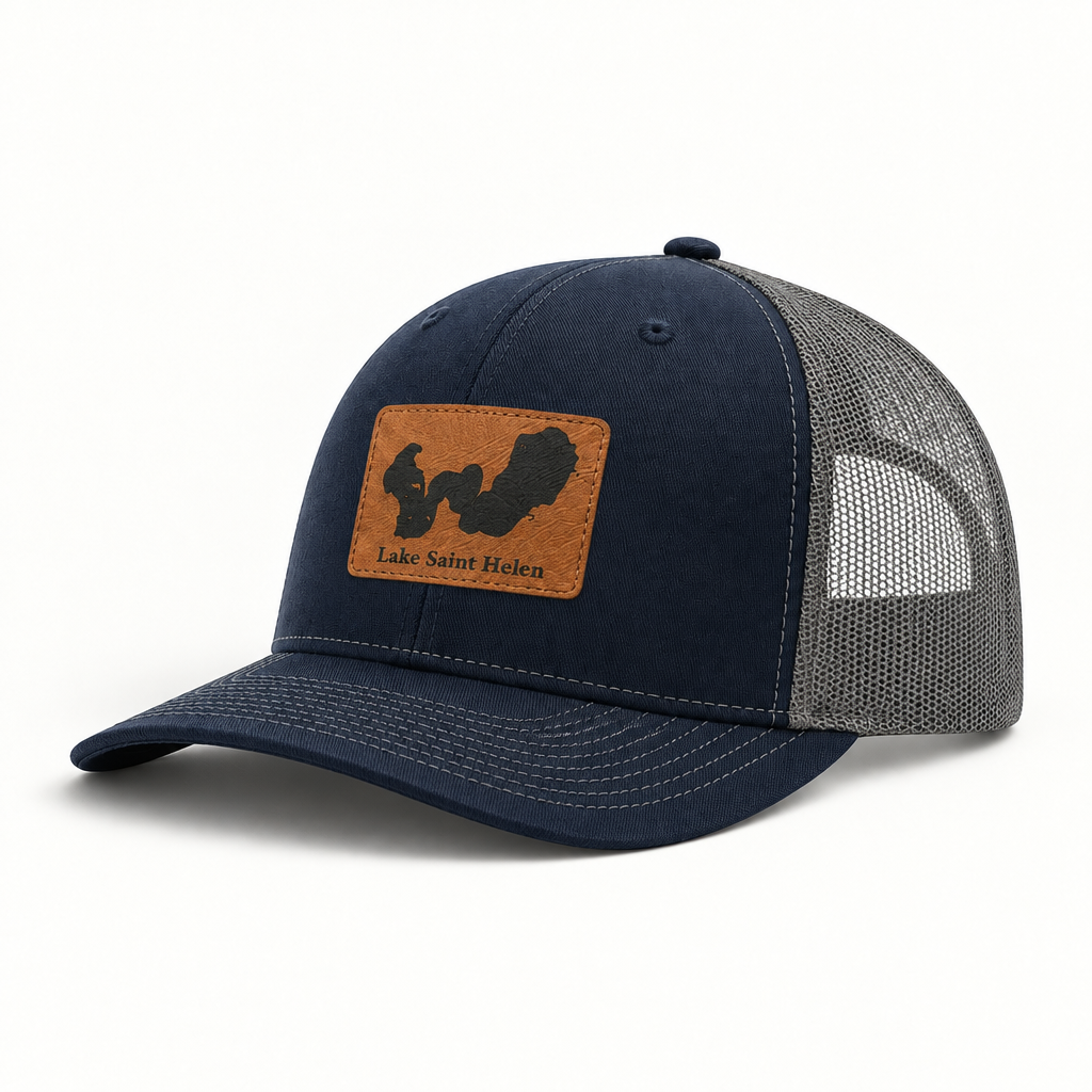 Navy trucker hat with tan logo patch, gray mesh back, curved brim, snap button