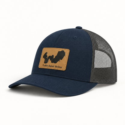 Navy trucker hat with tan logo patch, gray mesh back, curved brim, snap button
