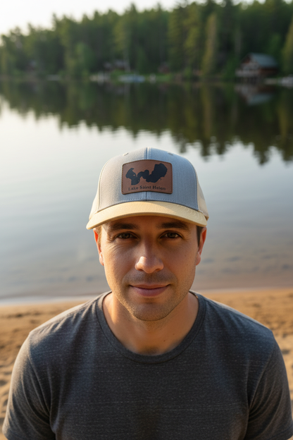 Lake Saint Helen Michigan leatherette patch trucker hat worn by model on calm inland lake shoreline – Keeko Designs