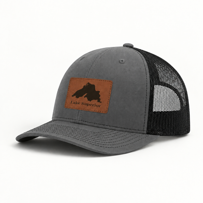 Dark gray trucker hat with black mesh back and tan leather “Lake Superior” patch