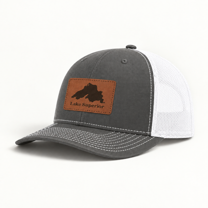Charcoal gray trucker hat with white mesh back and tan leather “Lake Superior” patch