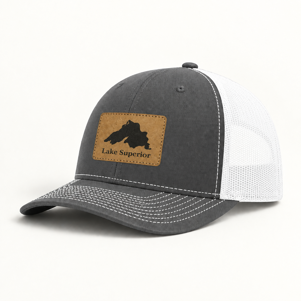 Charcoal gray trucker hat with white mesh back and tan “Lake Superior” patch