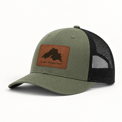Olive green trucker hat with black mesh back and tan leather “Lake Superior” patch