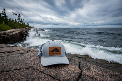 Light gray trucker cap with brown Lake Superior patch and blue mesh back, curved brim