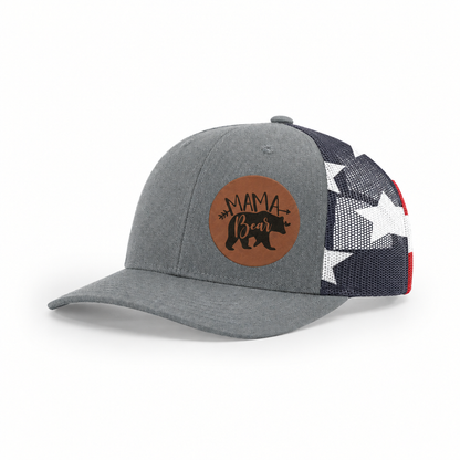 Gray trucker cap with black mesh back and tan “Mama Bear” patch, side view.
