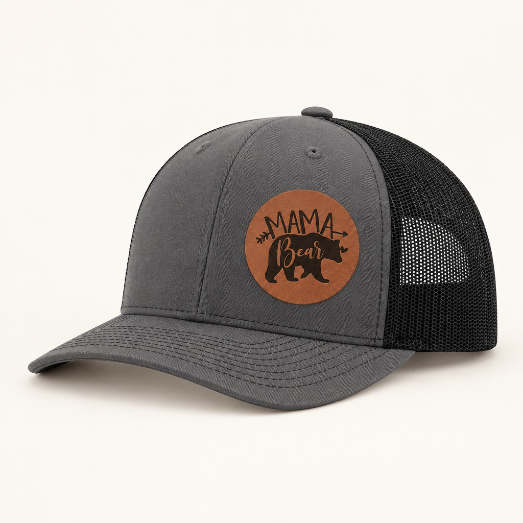 Charcoal gray trucker cap with black mesh back and tan “Mama Bear” patch.