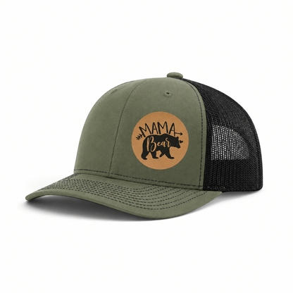 Olive green trucker hat with black mesh back and tan “Mama Bear” patch.