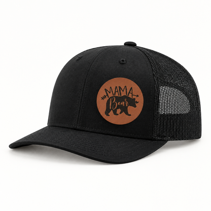 Black trucker hat with tan “Mama Bear” patch and black mesh side panels.