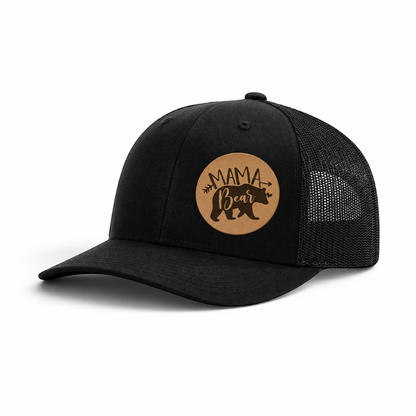 Black trucker hat with tan “Mama Bear” patch and black mesh back panels.