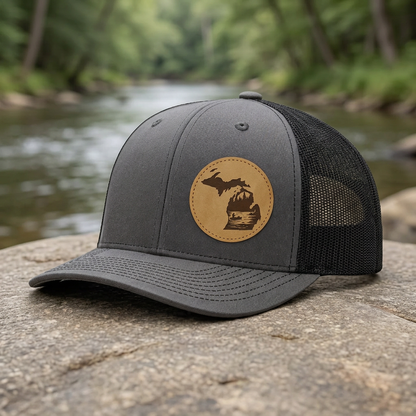 Charcoal trucker cap with tan circular fishing patch and front curved brim