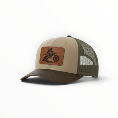 Beige and dark green trucker hat, front dirt bike patch and mesh side panels.