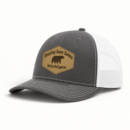 Dark gray trucker hat with white mesh sides and tan Sleeping Bear Dunes Michigan patch