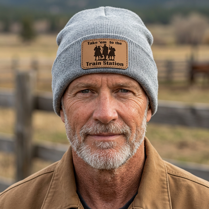 Heather gray knit beanie with rectangular leather-look patch reading Take 'em to the Train Station